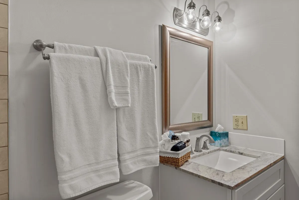 A refreshing bathroom scene with neatly arranged towels, a clean sink, and a mirror. The abundant natural light and inviting atmosphere highlight the care taken in providing essential amenities for guest comfort.